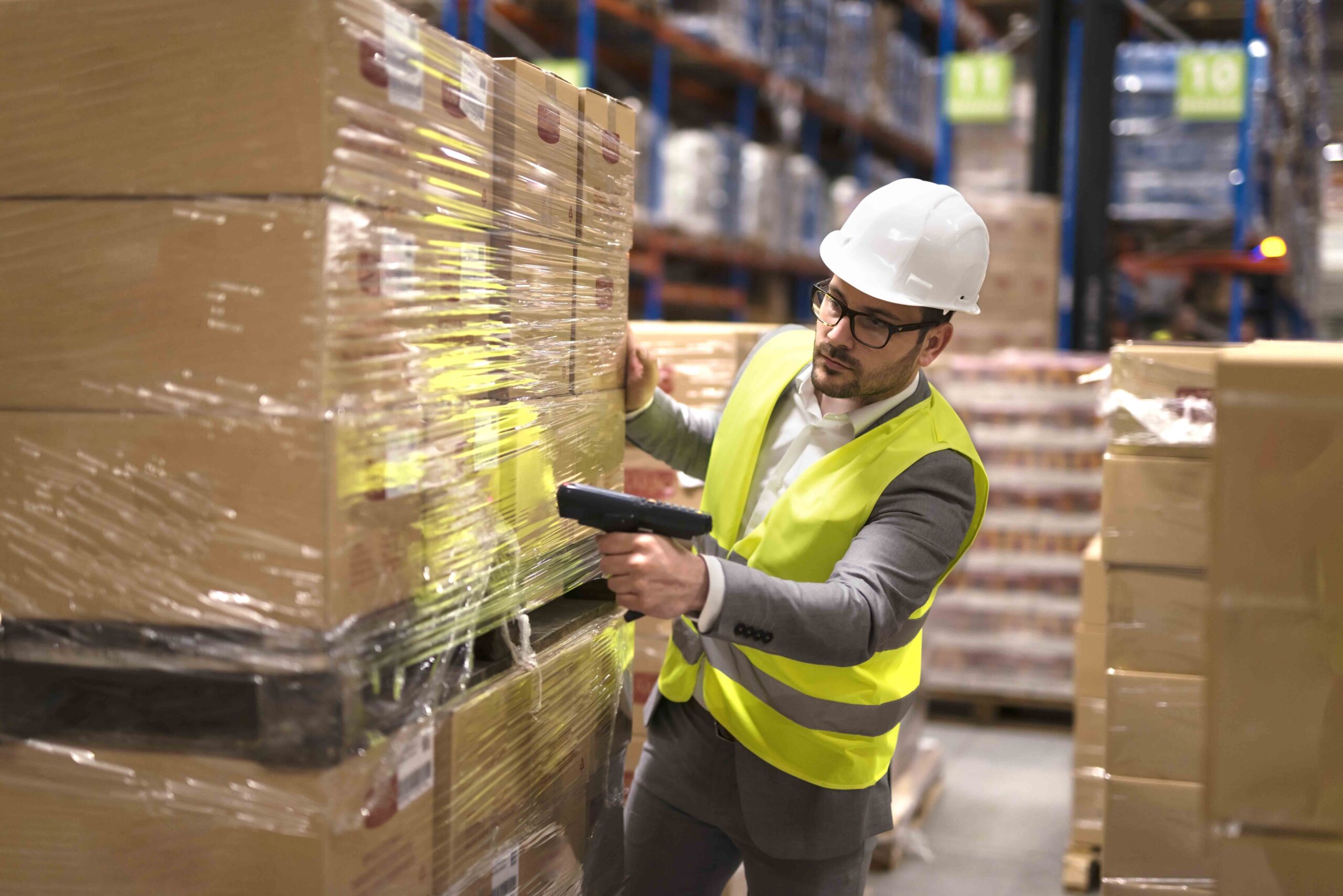 Male warehouse worker using bar code scanner to analyze newly ar