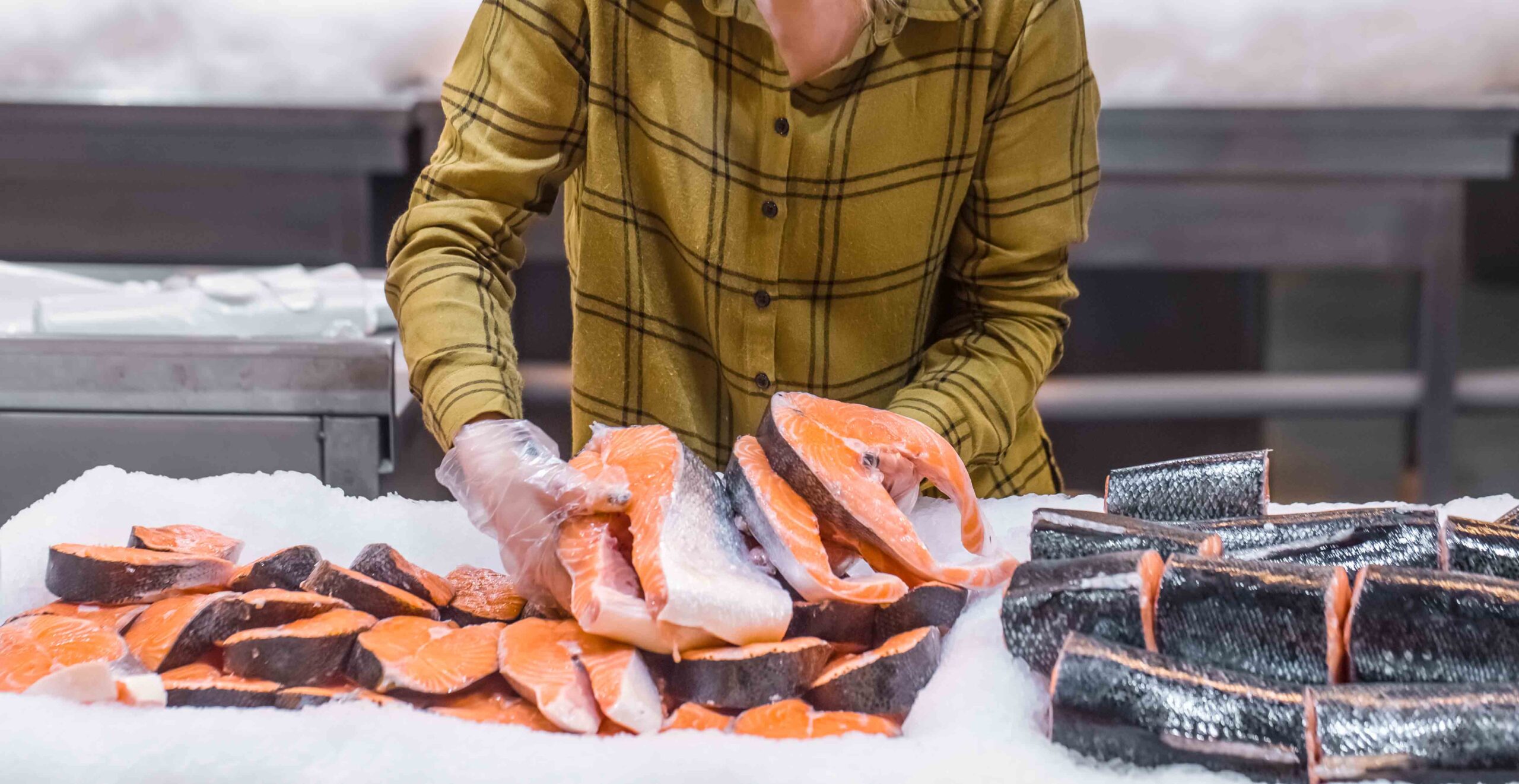 Woman in the supermarket. Beautiful young woman holding a salmon fish in her hands