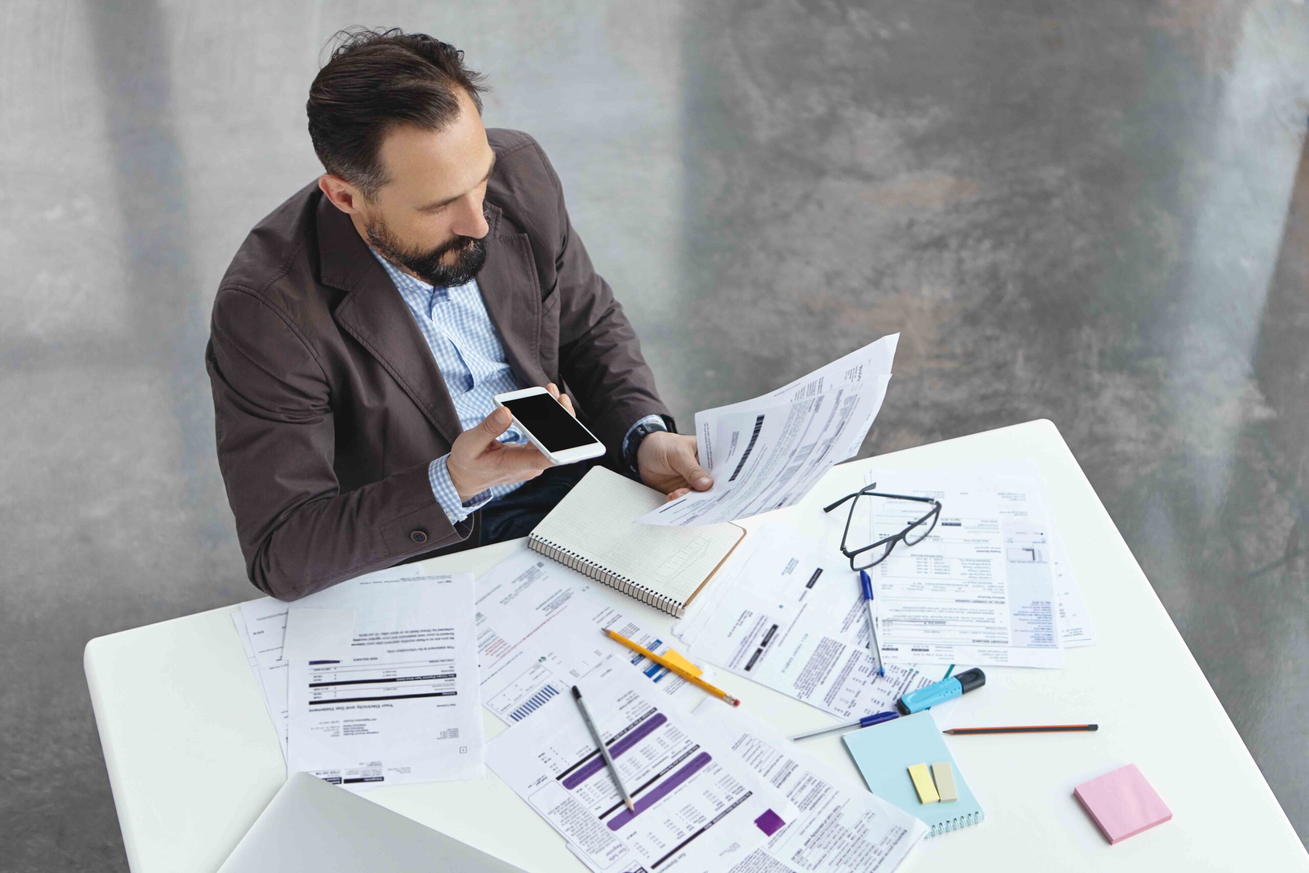 Portrait of busy male office worker makes voice call, discuss documents with partner, compare result, try to predict wastes for next month