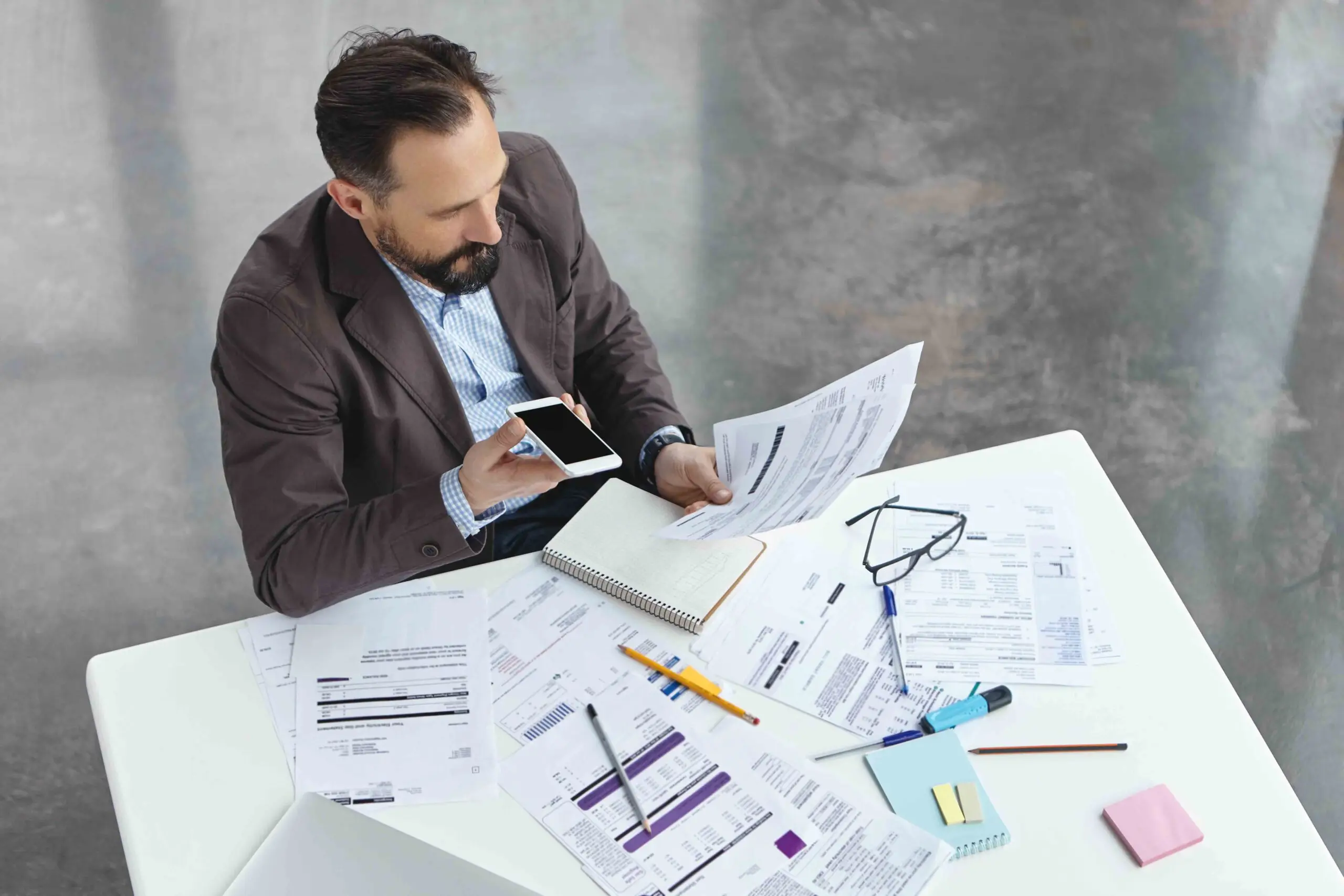 Portrait of busy male office worker makes voice call, discuss documents with partner, compare result, try to predict wastes for next month