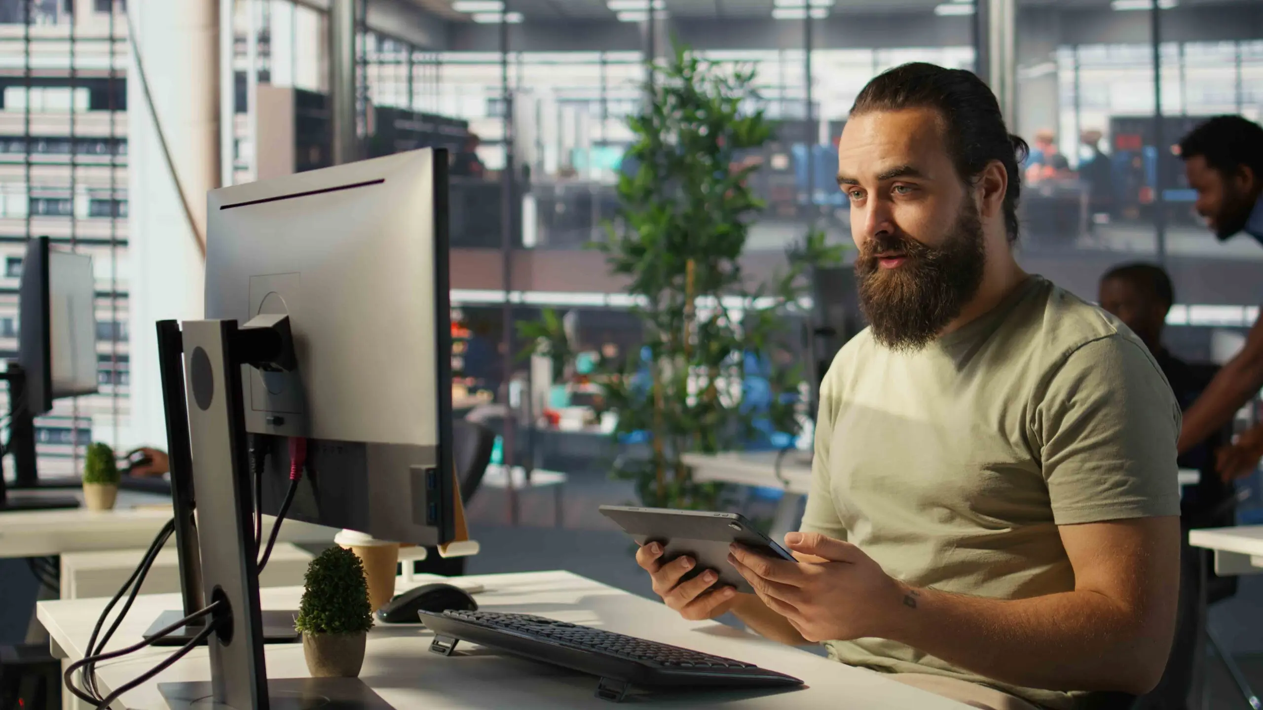 Employee looking at PC monitor, drinking coffee, checking data